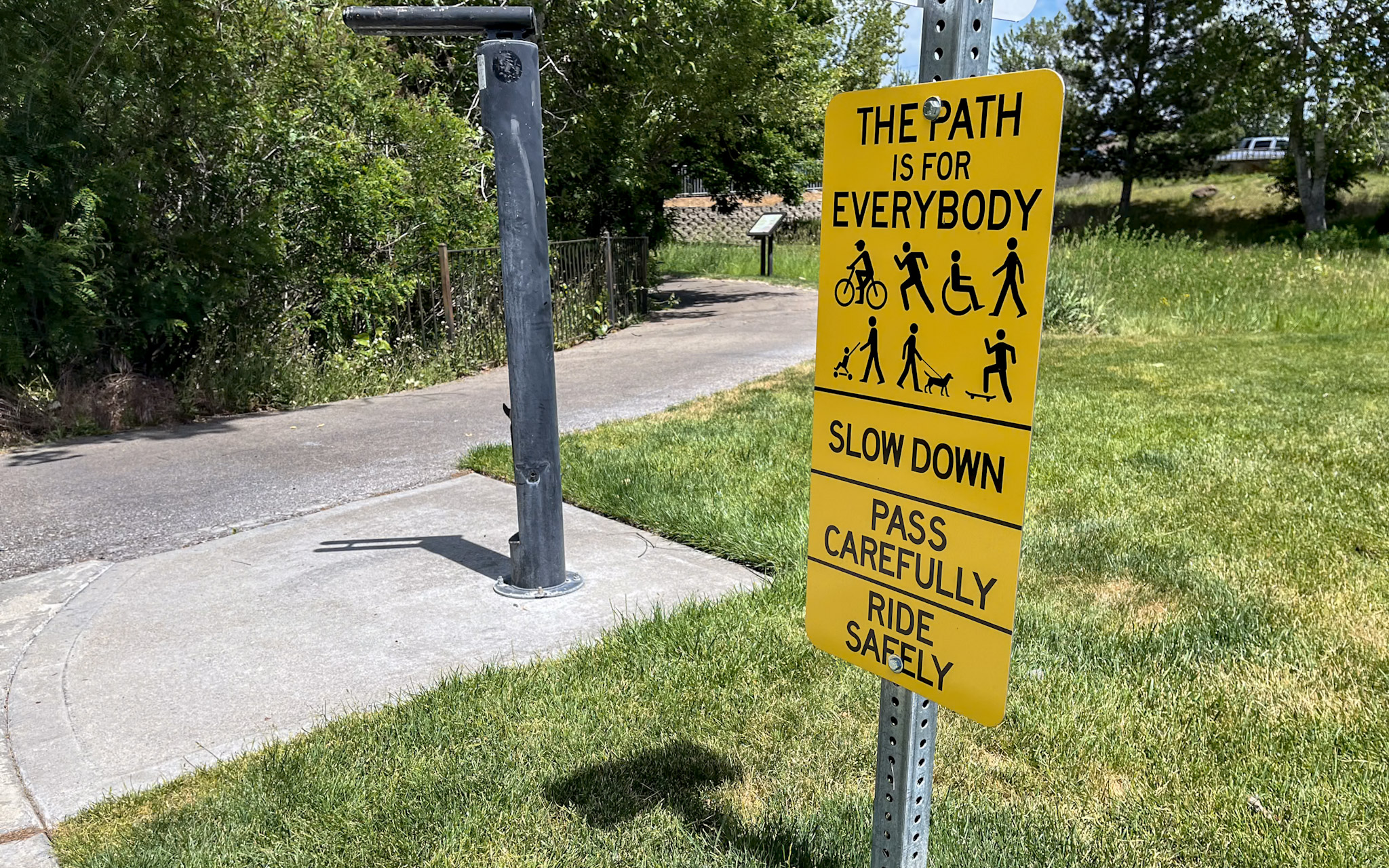 The Path is for Everybody sign along greenbelt. Slow down pass carefully ride safely